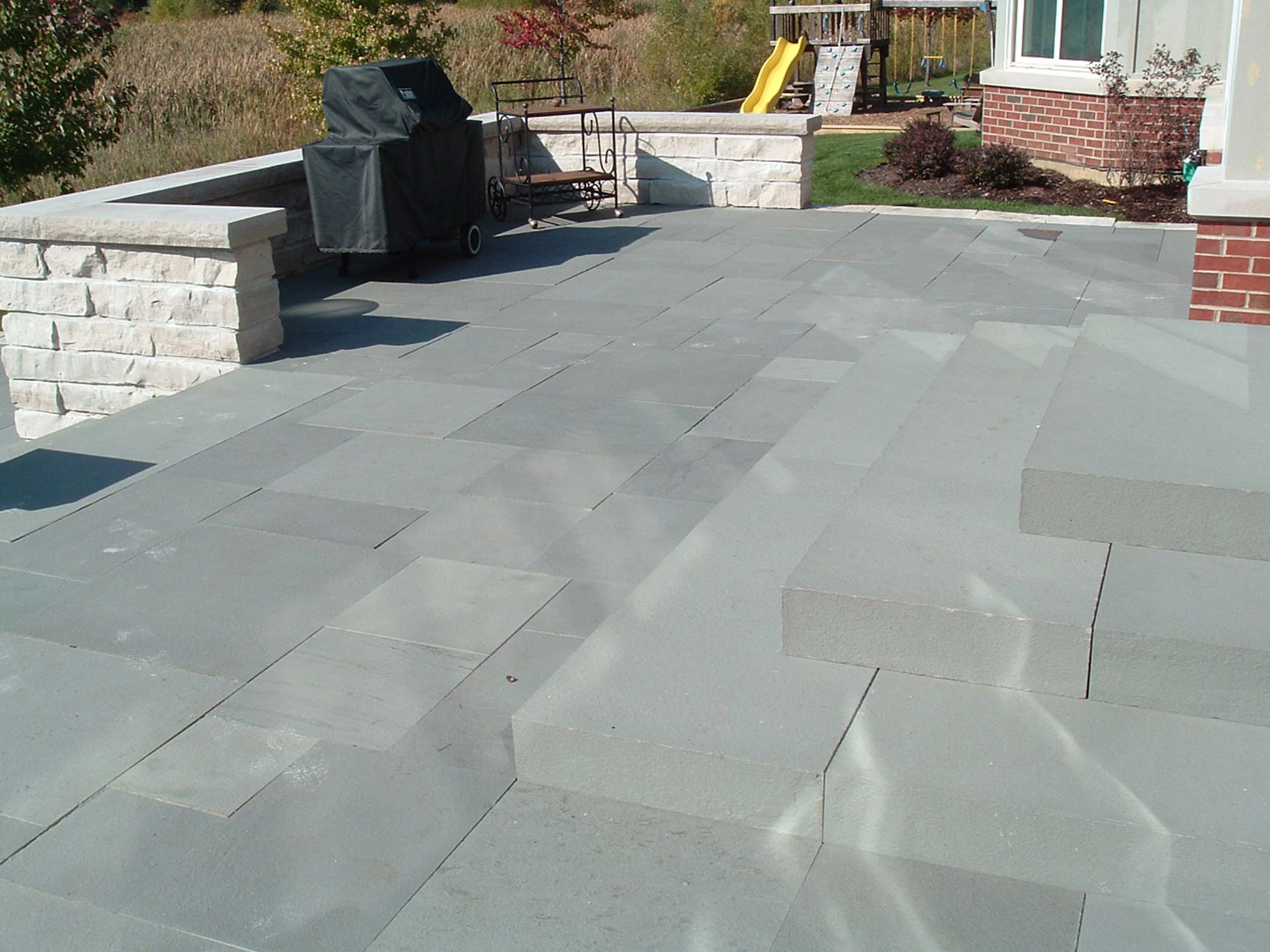 Smooth stone patio with a stone wall surrounding a barbeque grill